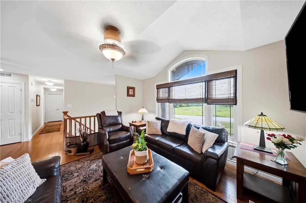 Living room with dark leather seating, a patterned rug, and a large window overlooking green fields.