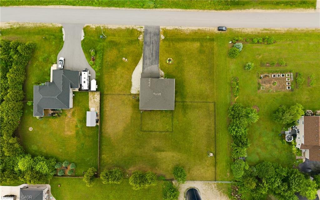 Aerial view of a grassy residential lot with a detached building and garden area.