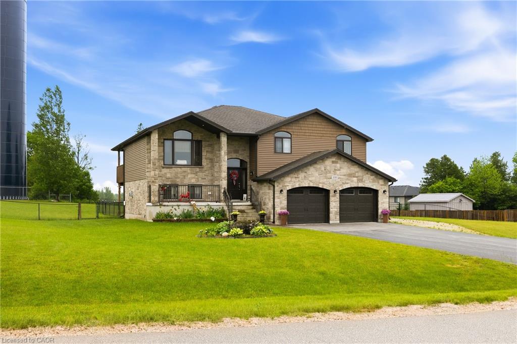 Two-story stone-and-siding home with a double garage, landscaped lawn, and paved driveway.