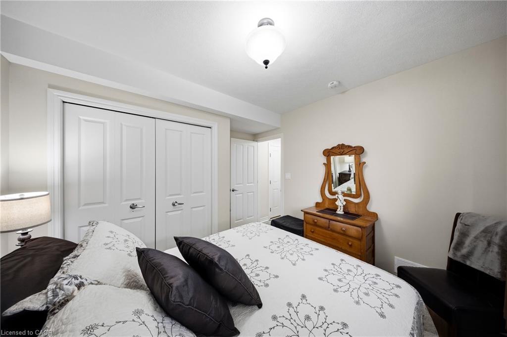 Furnished bedroom with floral bedding, sliding closet doors, and a wooden dresser with an ornate mirror.