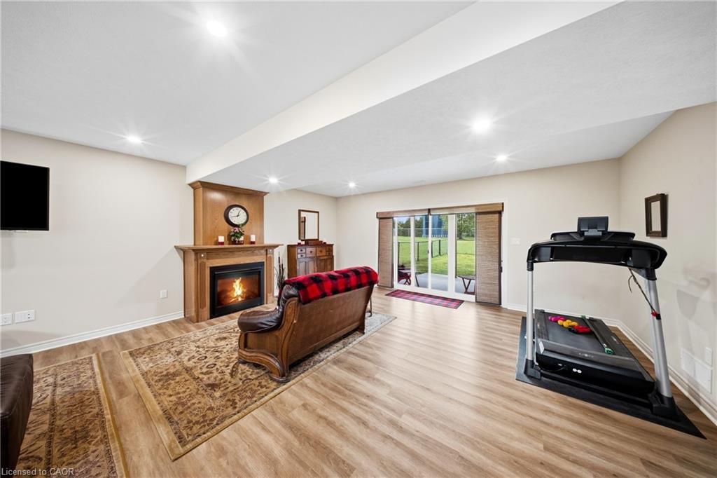 Furnished recreation room with a fireplace, treadmill, and sliding doors opening to a grassy yard.