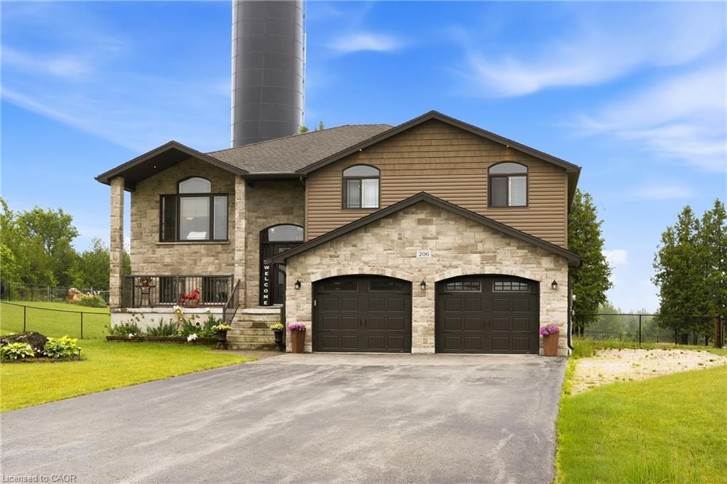 Two-story stone-and-siding house with a double garage, wide driveway, and silo behind the roof.
