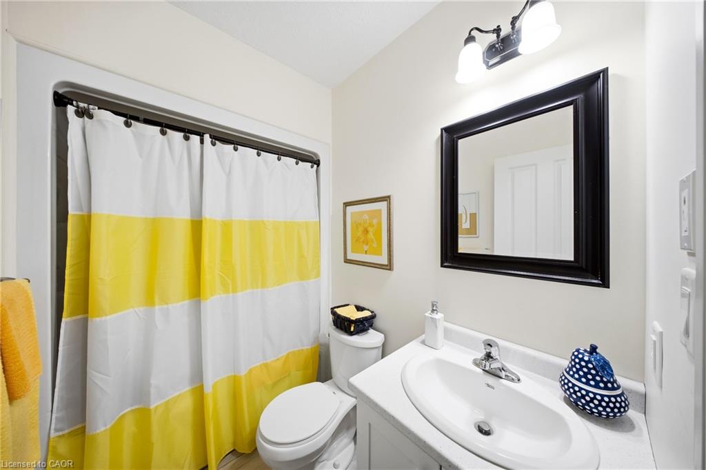 Bathroom with a white vanity, black-framed mirror, and yellow-striped shower curtain.