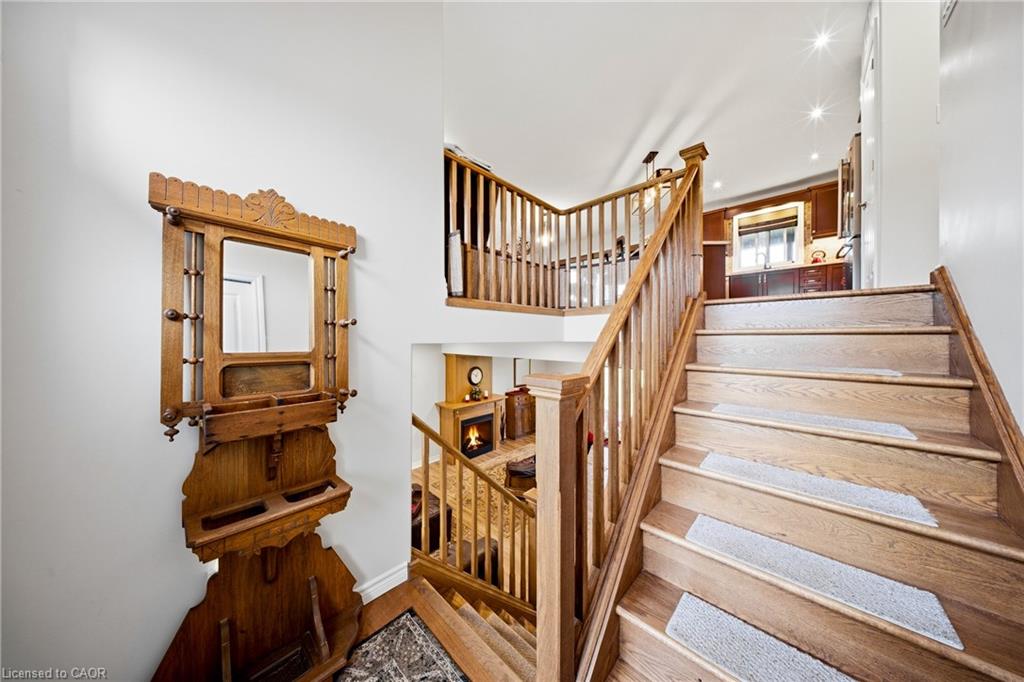 Wooden staircase with carpeted treads, an ornate hall mirror, and a view toward a fireplace below.