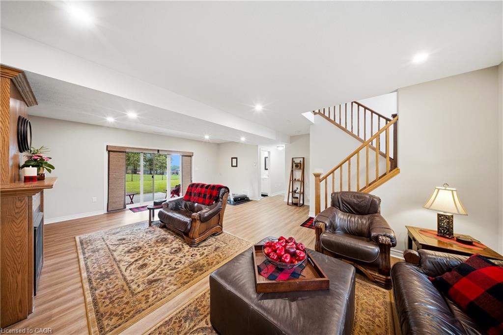Living room with leather seating, patterned rug, sliding glass doors, and a wooden staircase.