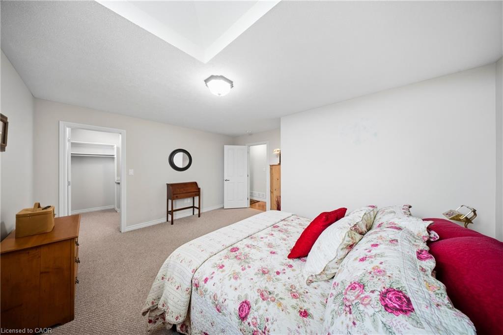 Bedroom with a floral quilted bed, red pillows, beige carpet, and an open closet.