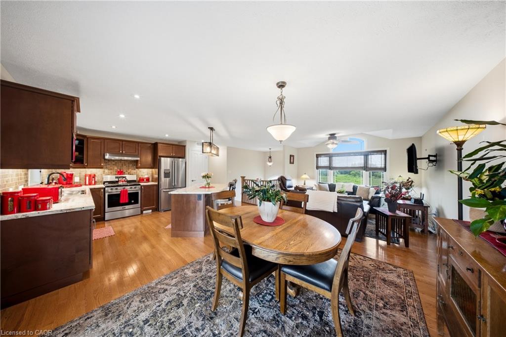 Open-plan kitchen and dining area with dark wood cabinetry, round table, and adjoining living room.