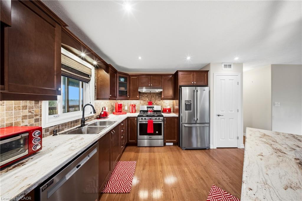 Kitchen with dark wood cabinets, granite counters, stainless steel appliances, and a window overlooking water.