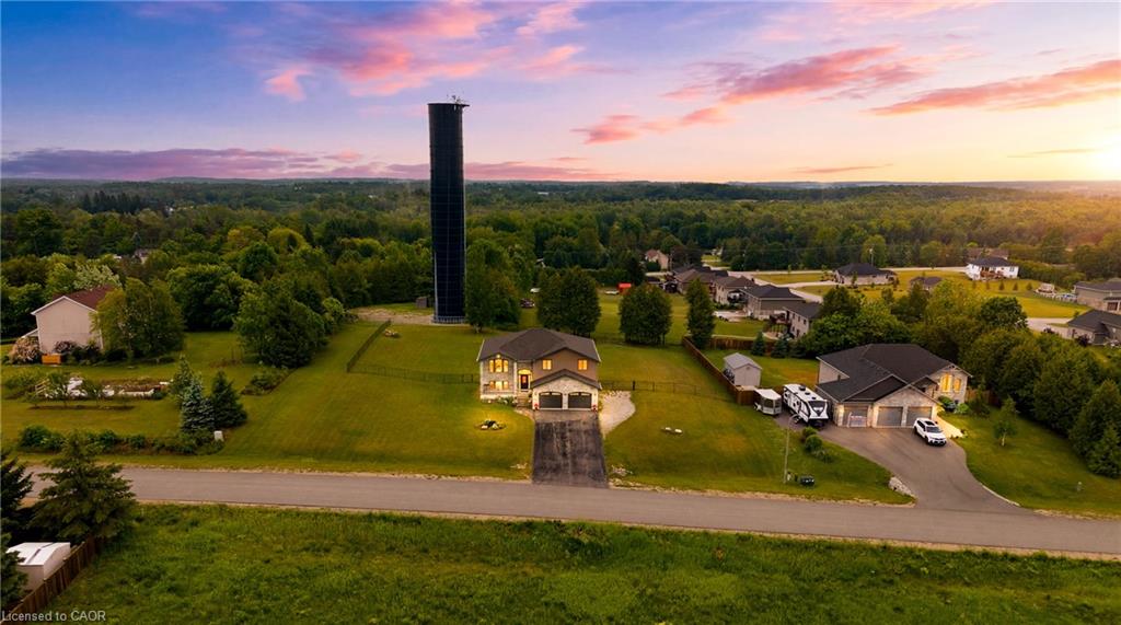 Aerial view of a two-story house and lawn, with a tall black silo behind it.