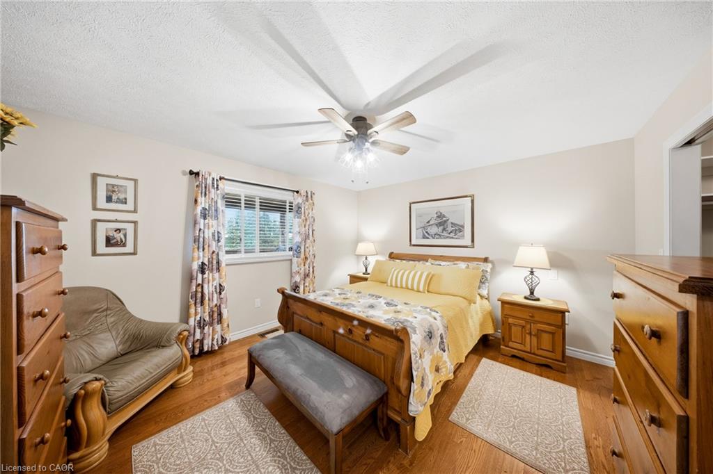 Furnished bedroom with a wooden bed, yellow bedding, floral curtains, and a leather loveseat.