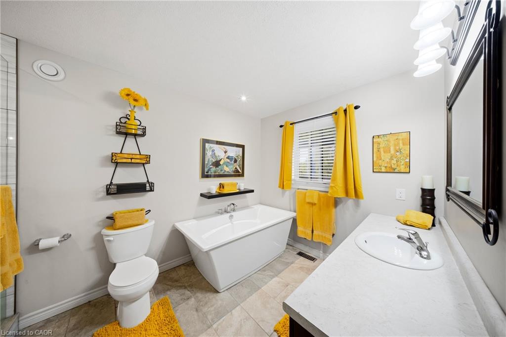 Bathroom with a freestanding tub, long white vanity, and bright yellow curtains and towels.