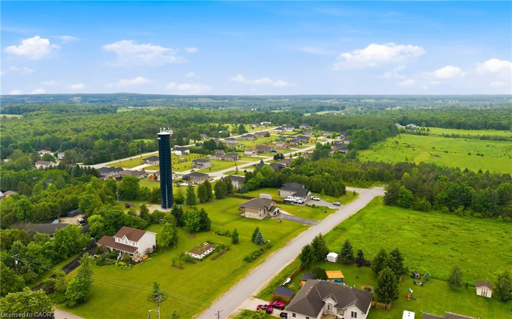 Aerial view of homes and fields along a rural road, with a tall water tower.