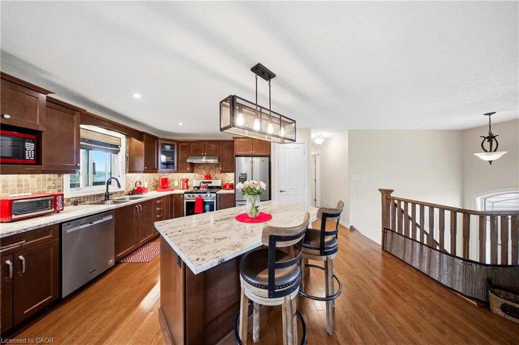 Kitchen with dark wood cabinets, stainless steel appliances, and a large island with bar stools.