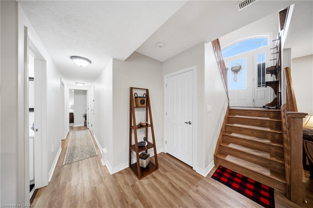 Bright home entryway with a wooden staircase, tall front-door window, and long hallway.