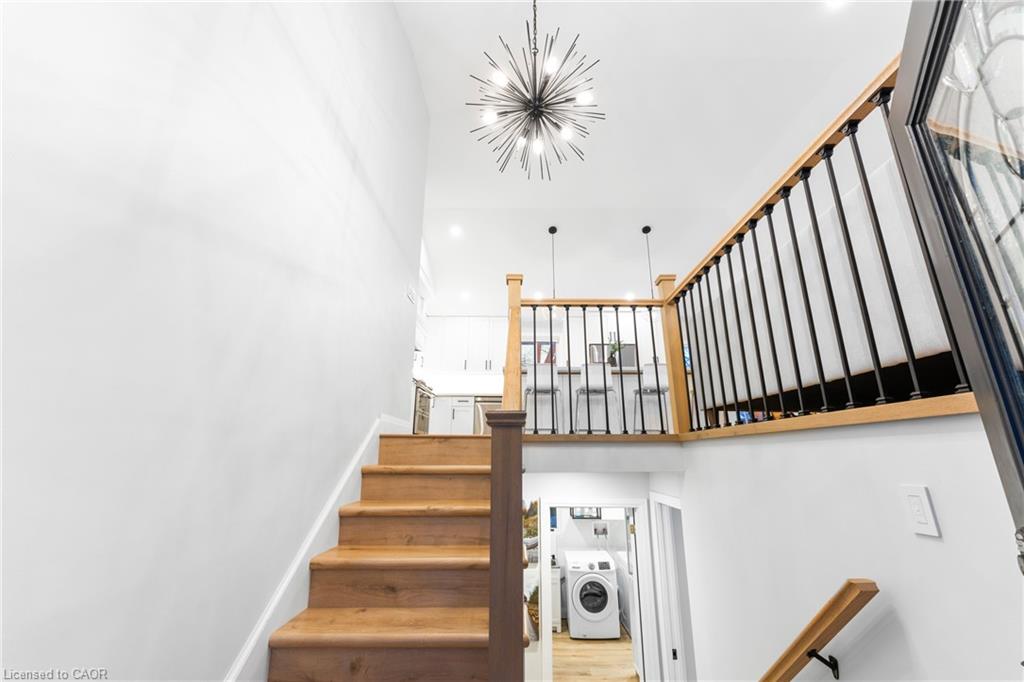 Wooden staircase with black metal railings, an upper landing, and a starburst chandelier.