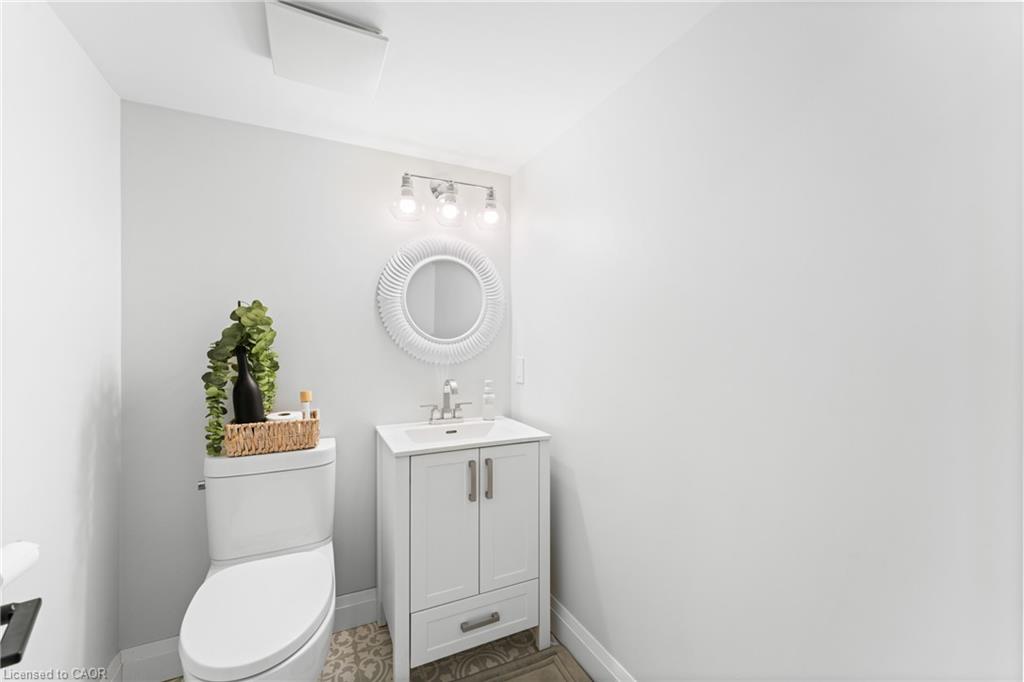 Bathroom with white toilet and vanity, round mirror, and patterned tile floor.