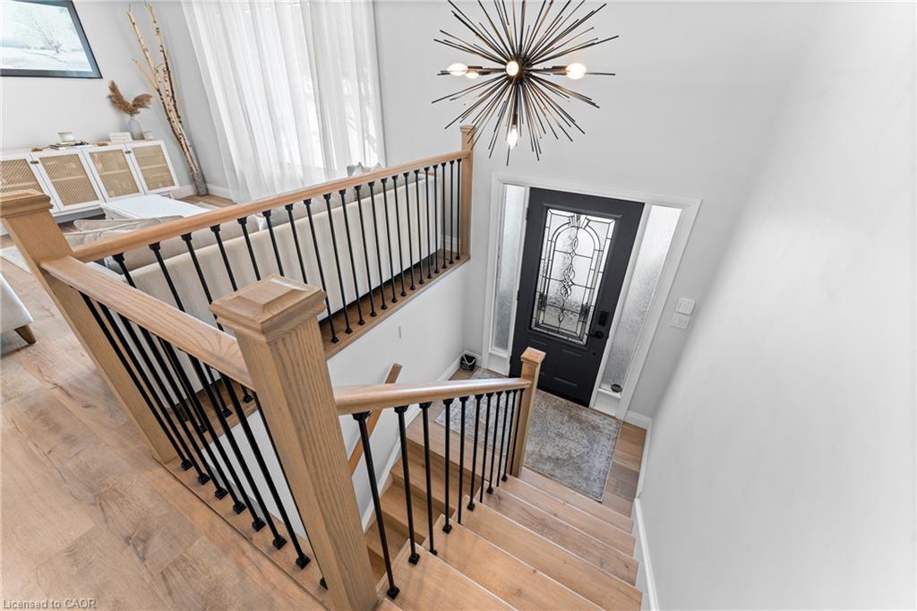 Two-story entryway with a wood staircase, black railings, and a decorative glass front door.