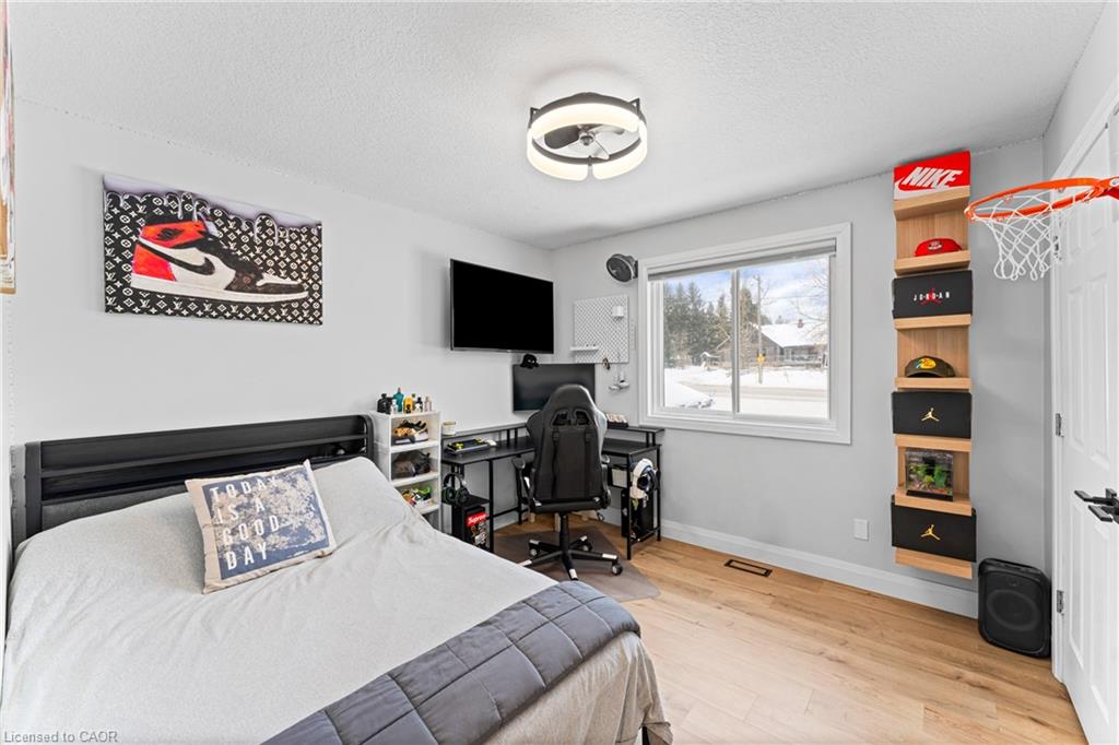 Bedroom with a gaming desk and chair beside a window, plus a wall-mounted sneaker display.