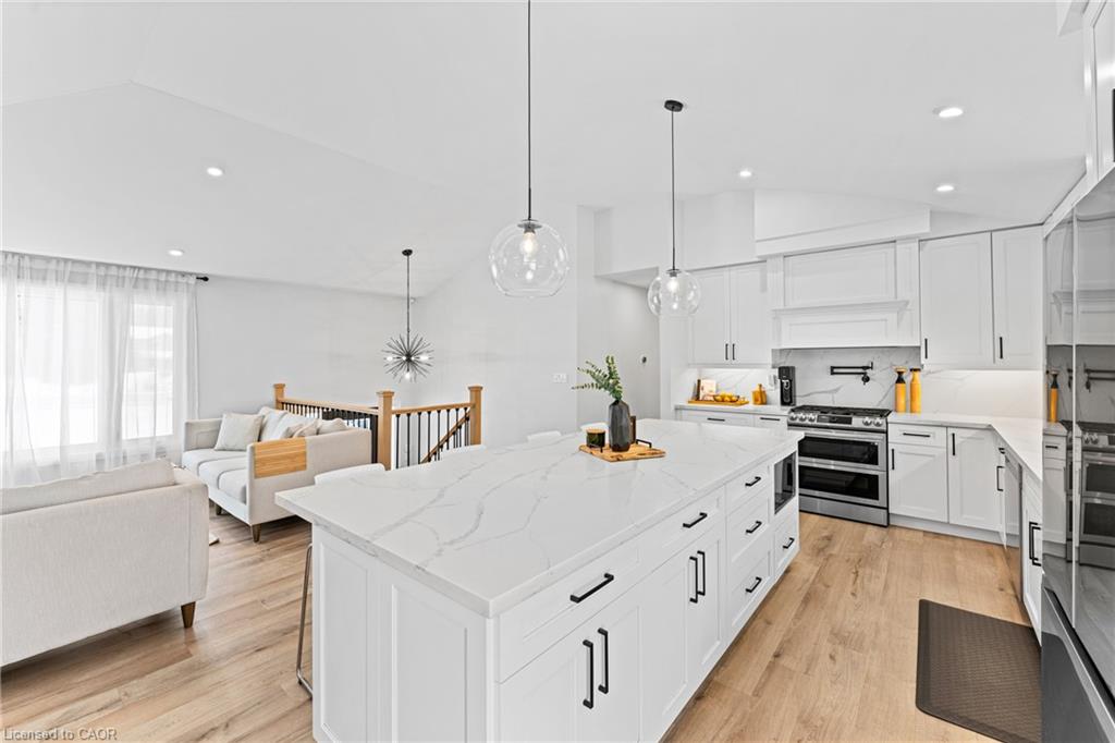 Open-concept kitchen with a large veined stone island, white cabinetry, and adjoining living area.