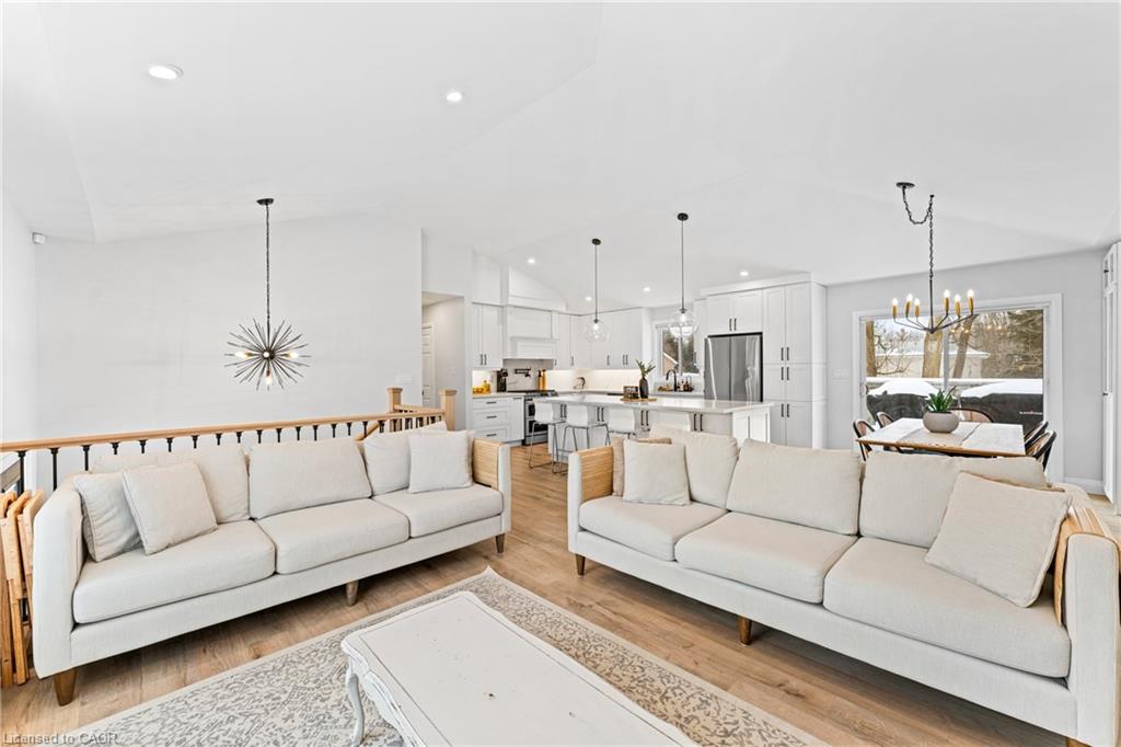 Open-concept living room with two cream sofas, a white kitchen island, and dining area by snowy windows.
