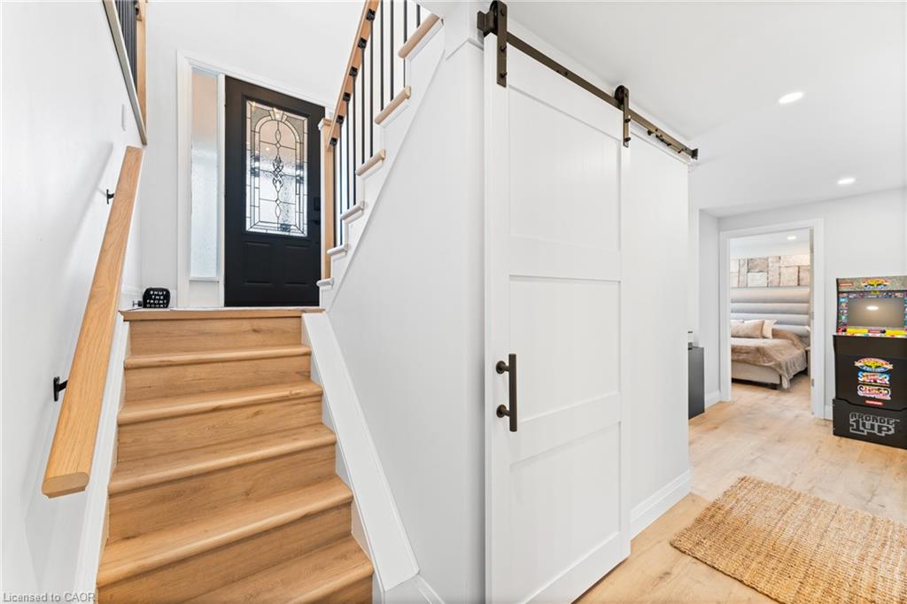 Foyer with wood stairs leading to a black glass-paneled door and a white sliding barn door.