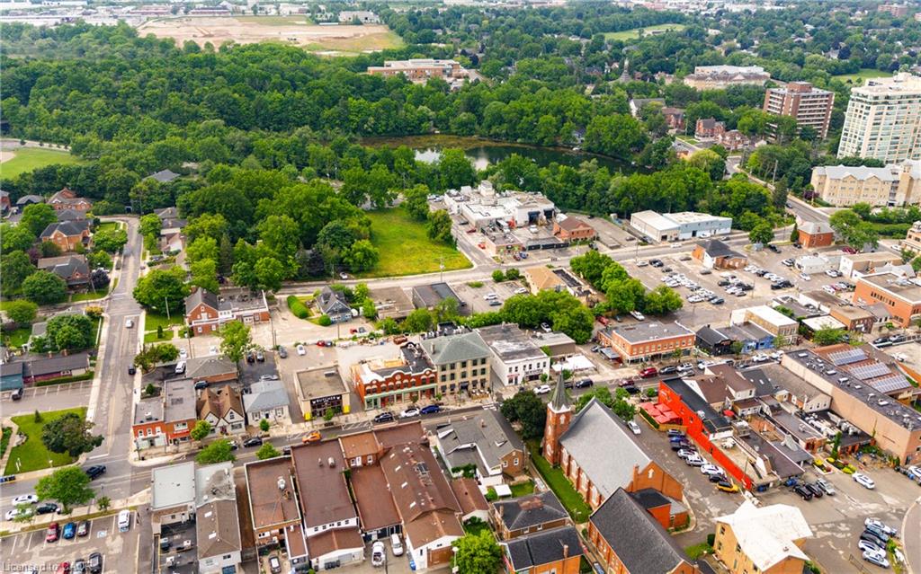 Aerial view of a town center with a leafy river corridor and low-rise commercial buildings.