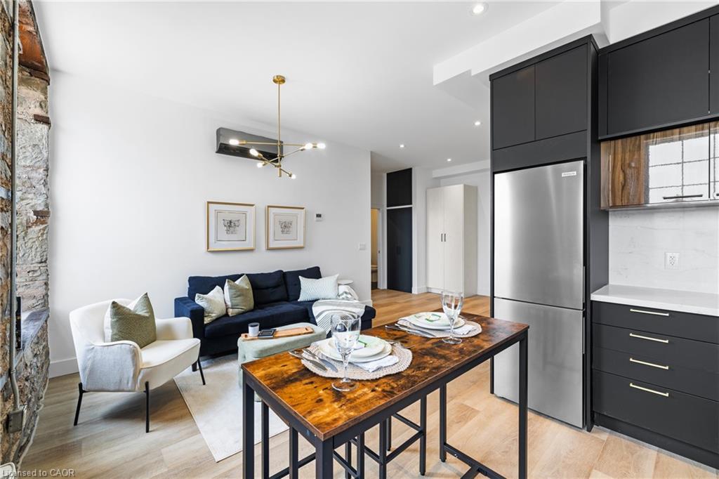Open-plan condo living room and kitchen with a stone feature wall and dark cabinetry.