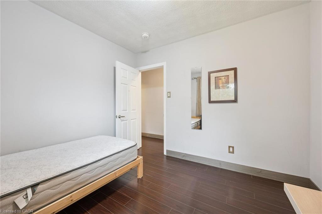 Bedroom with a low wooden bed frame, mattress, dark flooring, and an open door to the hallway.