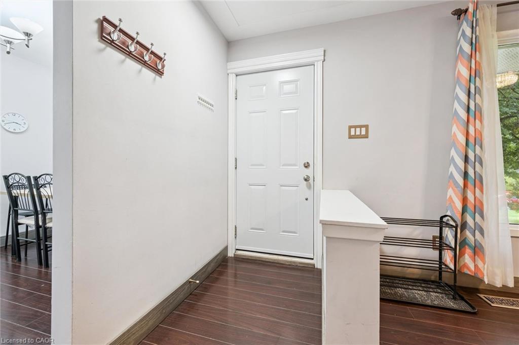 Entry foyer with a white paneled front door, dark wood flooring, and a patterned curtain.