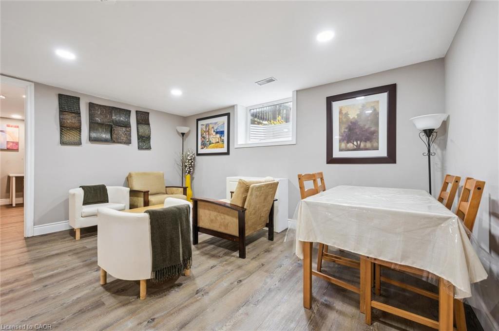 Dining and sitting area with a covered table, upholstered chairs, and gray wood-look flooring.