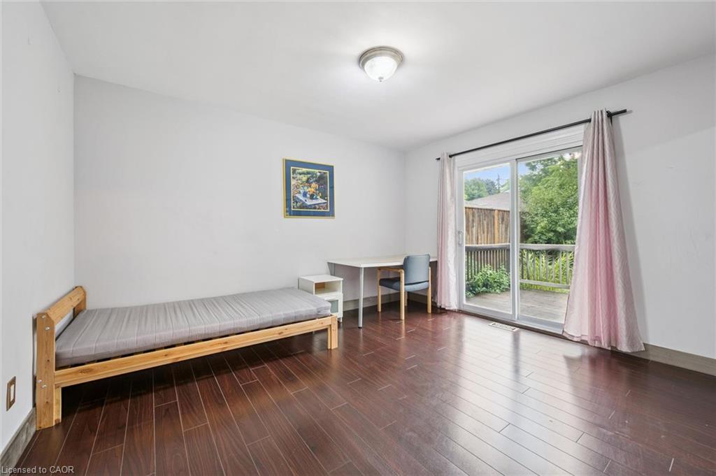 Bedroom with a wooden single bed and desk beside sliding doors to a deck.