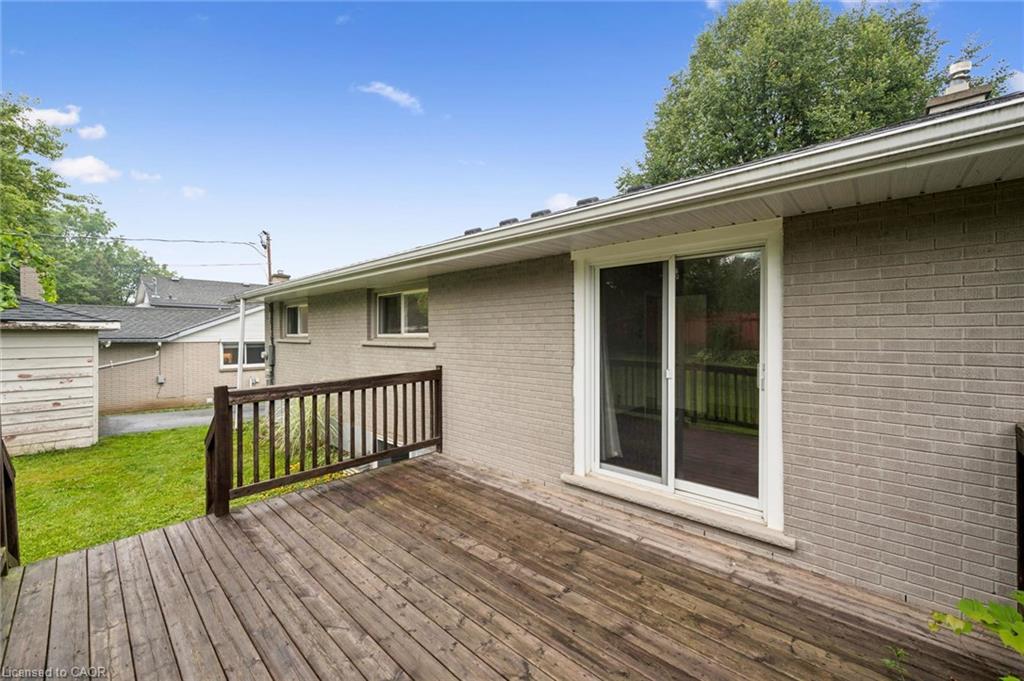 Wooden deck beside the home’s brick exterior, with sliding glass doors and a small lawn.