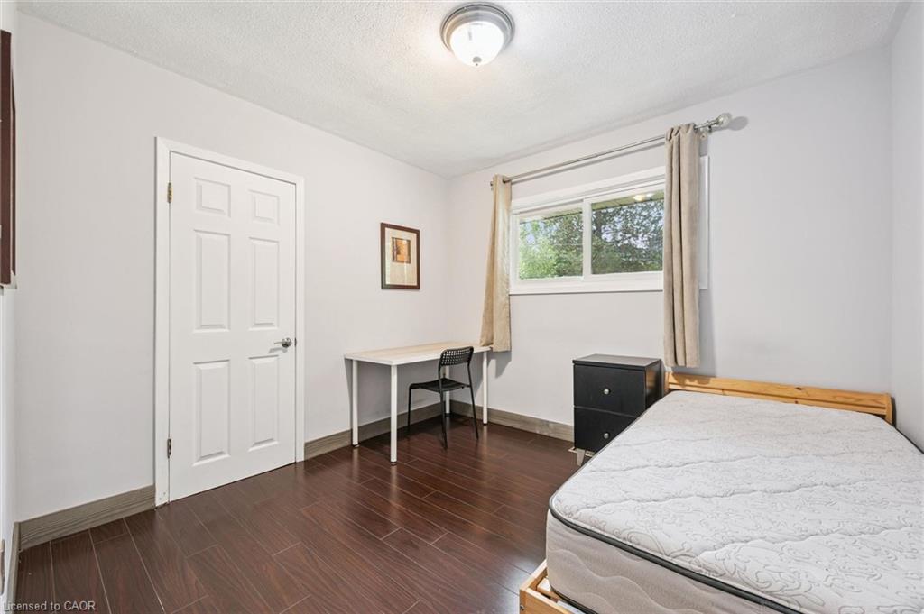 Bedroom with a desk beneath a curtained window and a bed in the foreground.