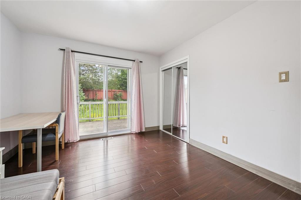 Bright room with dark wood flooring, mirrored closet doors, and a sliding glass door to a deck.
