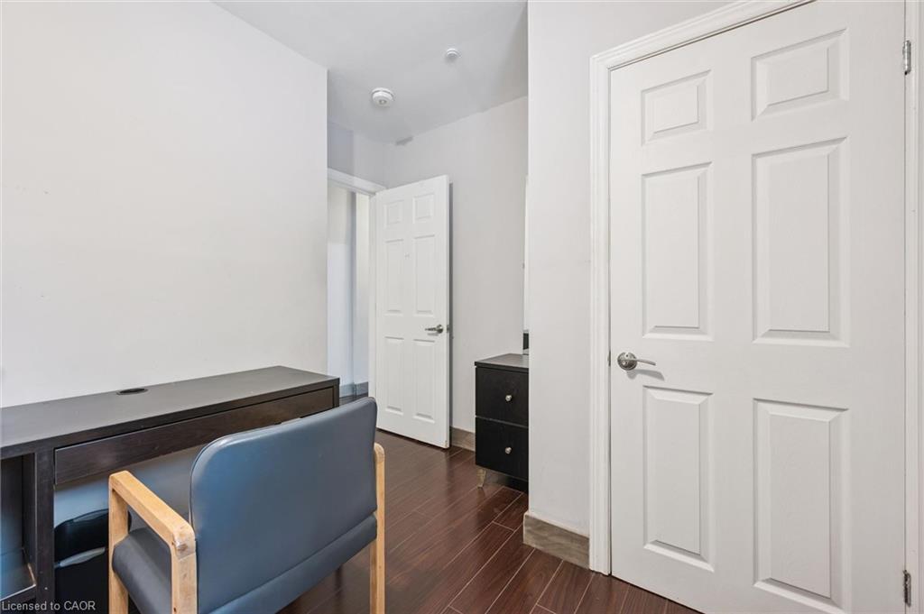 Home office with a dark desk, blue chair, wood flooring, and white paneled doors.