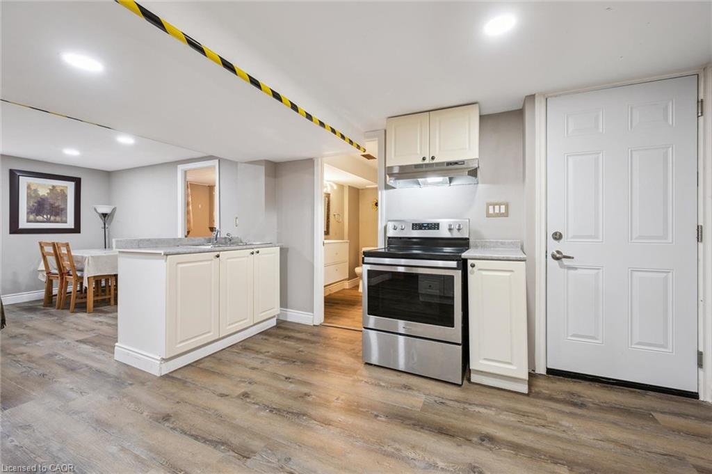Kitchen with white cabinets, stainless steel range, wood-look flooring, and an adjoining dining area.