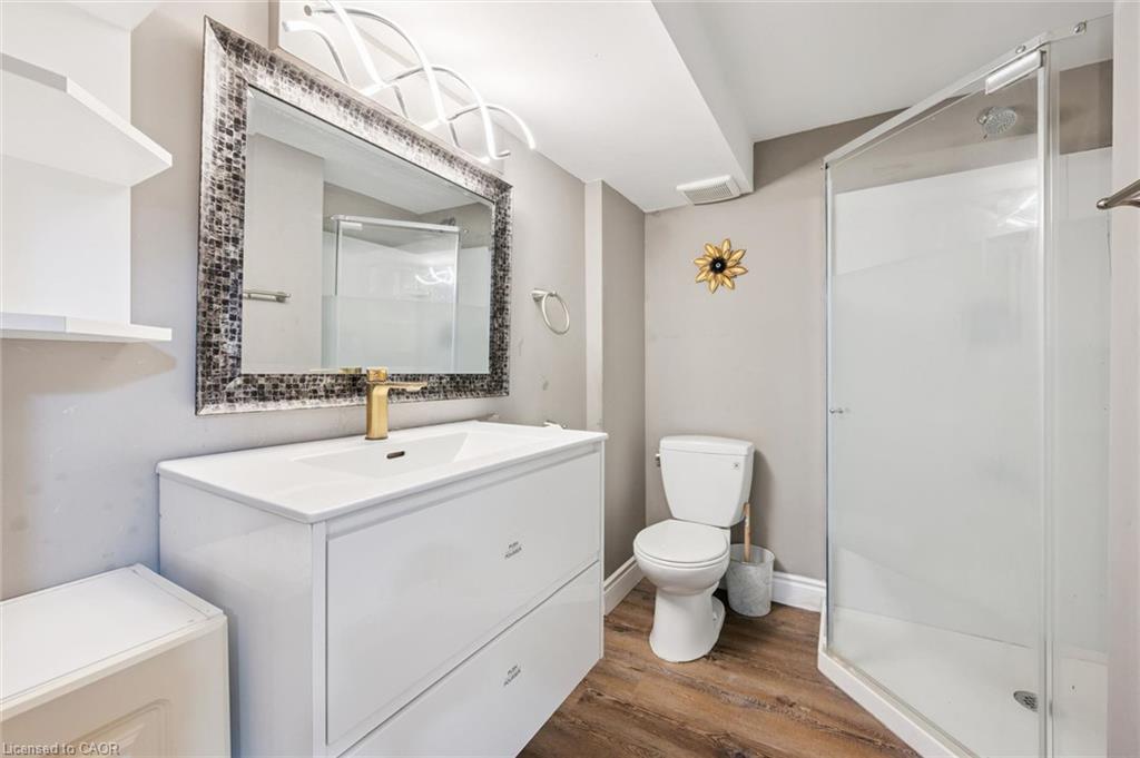 Bathroom with a white vanity, mosaic-framed mirror, and glass-enclosed shower.