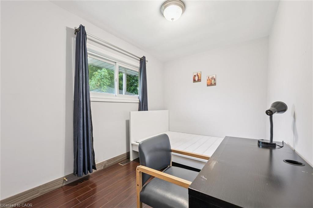 Bedroom with a single bed, dark desk and chair, and a window framed by navy curtains.