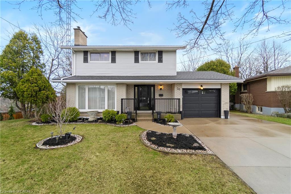 Two-story light-sided house with a dark garage, landscaped front lawn, and wide driveway.