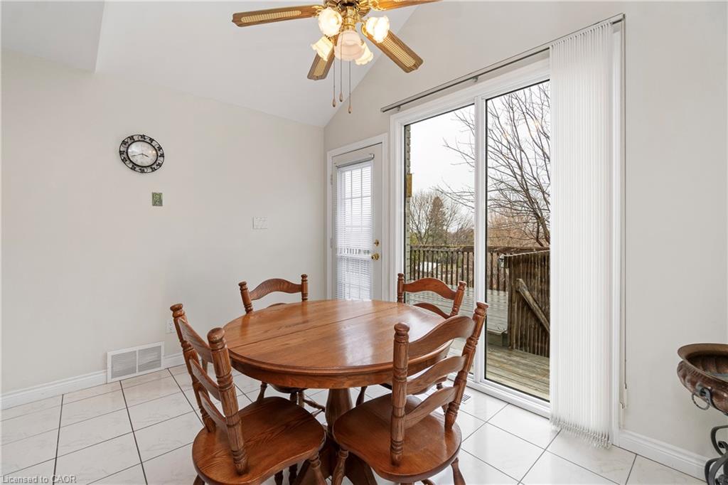 Dining area with a round wooden table beside a sliding glass door opening onto a deck.