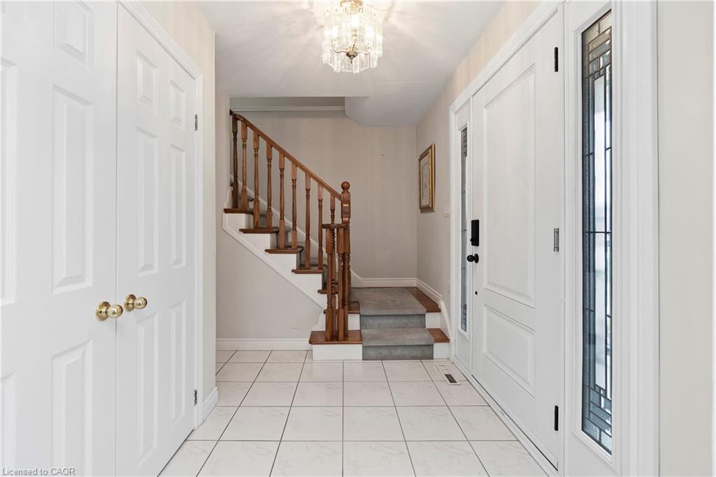 Front foyer with tiled floors, a wooden staircase, and a white glass-paneled entry door.