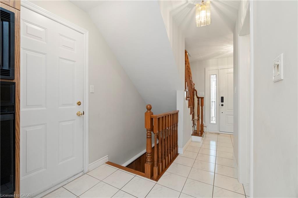 Tiled entry hall with a white front door and wooden railing around the stairwell.