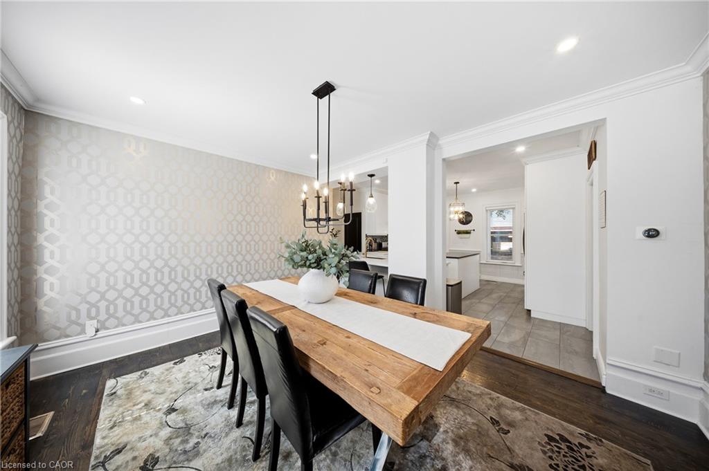 Dining room with a rustic wood table, black chairs, patterned wallpaper, and a chandelier.