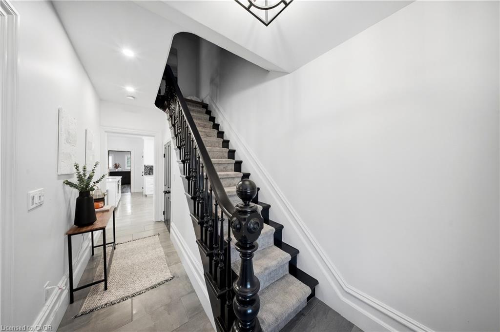 Bright entryway with a carpeted staircase, ornate black railing, and a slim console table.