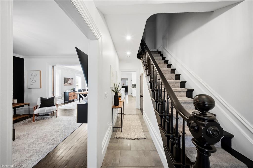 Entry hallway with a dark-railed staircase and a view into the furnished living room.