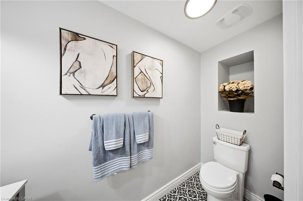 Bathroom with blue towels, abstract wall art, a flower-filled niche, and patterned floor tiles.