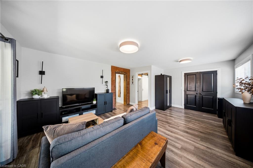 Furnished living room with a blue-gray sofa, dark entry doors, and wood-look flooring.