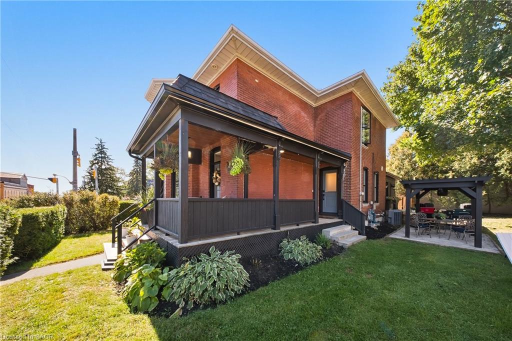 Two-story red-brick house with a deep covered porch and landscaped yard.