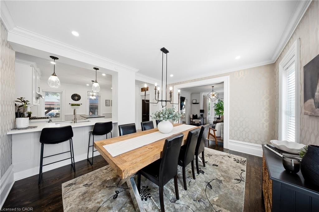 Dining room with a long wooden table and black chairs, open to a bright kitchen.