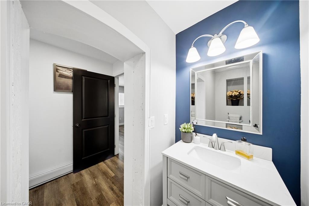 Bathroom vanity with a large mirror and three-light fixture on a blue accent wall.
